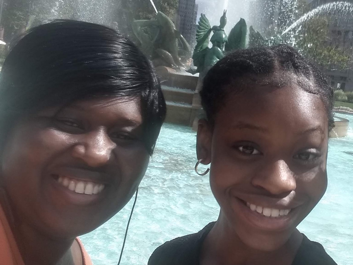 The McKingley family posed in a selfie together in front of a fountain in a city.